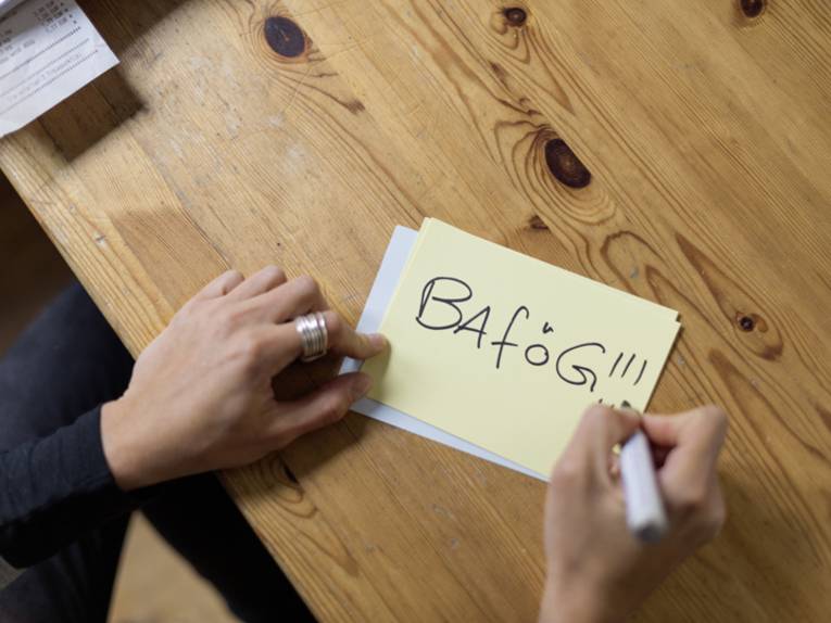 Jemand schreibt auf eine Karteikarte das Wort Bafög.