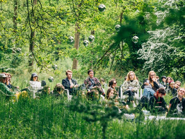 Menschen sitzen auf einer Wiese.