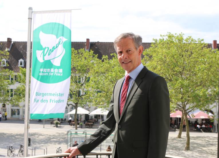Oberbürgermeister Udo Bausch vor der Flagge der Mayors for Peace