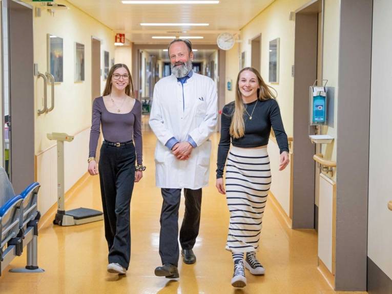 Zwei junge Frauen und ein Mann in weißem Kittel.