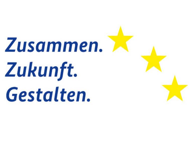 Das Logo zeigt die Worte "Zusammen.Zukunft.Gestalten" sowie drei gelbe Sterne am rechten oberen Rand