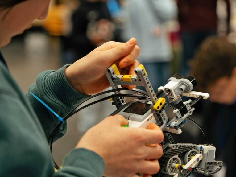 Kinderhände halten ein Robotermodell in den Händen.