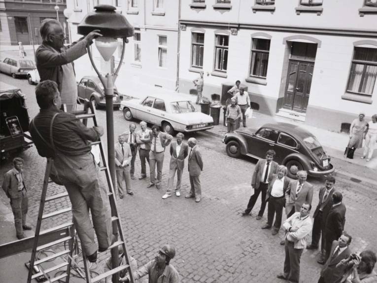 Arbeiter auf einer Leiter an einer Stra&szlig;enlaternen. Historische Schwarz-Wei&szlig;-Aufnahme