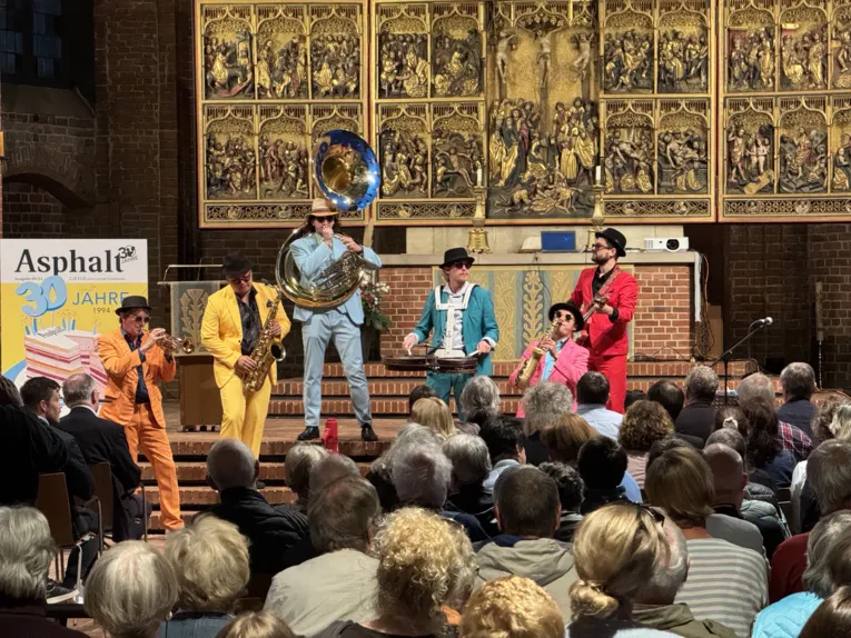 Band mit Blasinstrumenten in bunten Anz&uuml;gen spielt auf der Altarb&uuml;hne in der Marktkirche.
