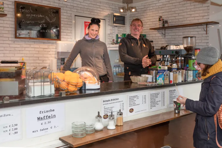 Verkaufspersonal und Kunden an einem Verkaufswagen f&uuml;r Kaffeespezialit&auml;ten und Snacks.