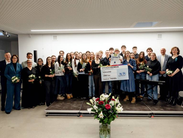 Eine große Gruppe hat sich für eine Scheckübergabe aufgestellt.