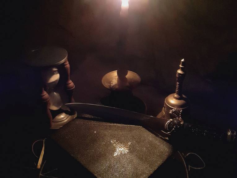 Stillleben mit antiken Dingen: ein Buch, ein Dolch, eine Sanduhr, eine Glocke und ein Kerzenständer