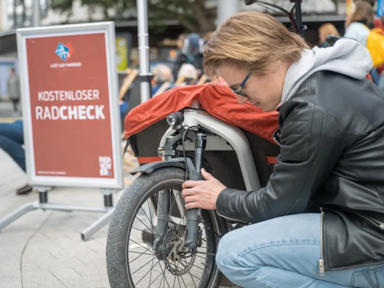 Ein Mann kniet vor einem Fahrrad und &uuml;berpr&uuml;ft die Radgabel.