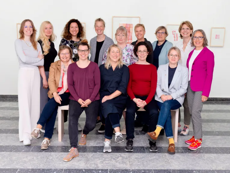 Eine Menschengruppe  aus vierzehn Personen, neun stehen, fünf sitzen.