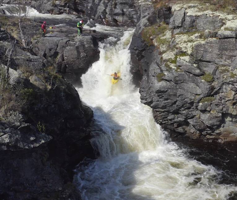 Ein Kajakfahrer befährt einen hohen Wasserfall.
