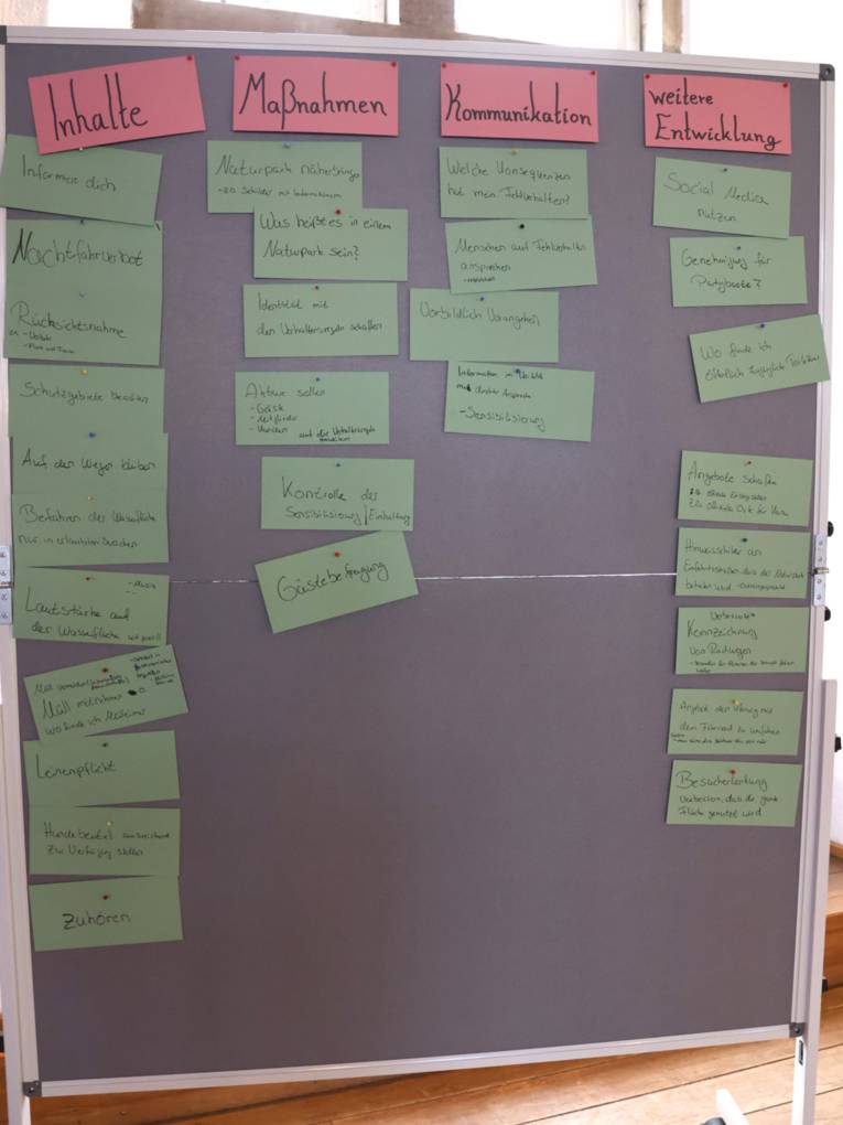 Auf Moderationskärtchen stehen die Ergebnisse eines Workshops. Die Kärtchen sind an eine Metaplanwand gepinnt.