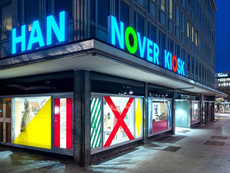 Beleuchtete Front vom Hannover Kiosk bei Nacht mit Blick in die Karmarschstraße