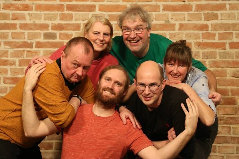 Menschen im Kreis vor einer Backsteinwand