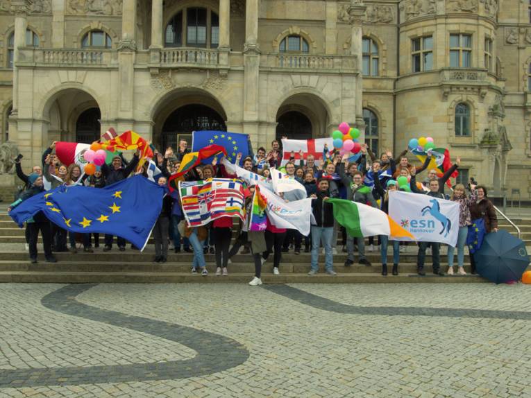 Menschengruppe mit vielen verschiedenen Flaggen auf der Treppe vor dem Neuen Rathaus in Hannover.