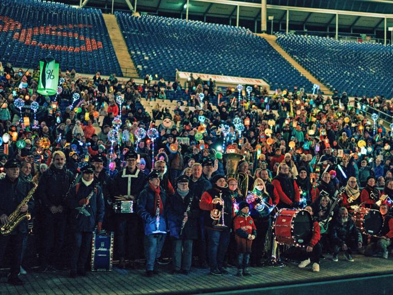 Kinder und Erwachsene mit Laternen im 96-Stadion.