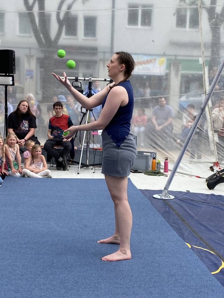 Alle Bälle im Blick jongliert eine junge Frau.