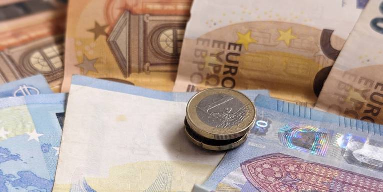 Mehrere Euromünzen liegen auf Euro-Geldscheinen