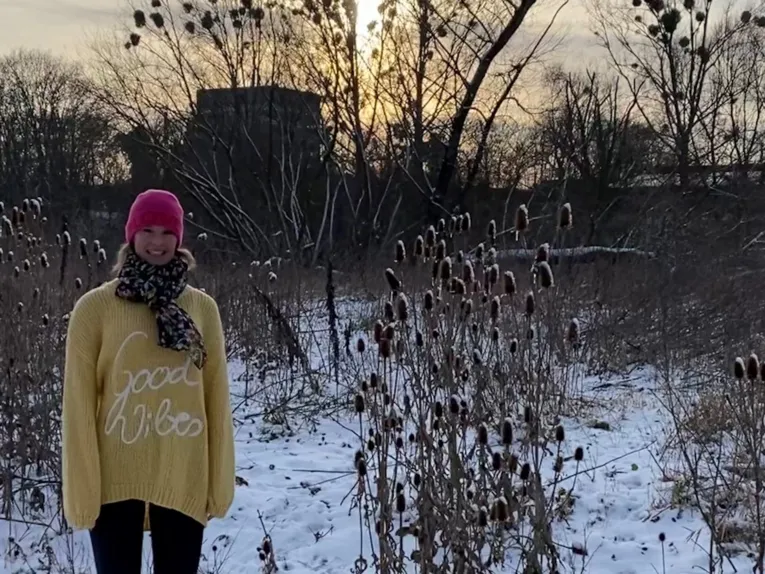 Eine Frau im gelben Strickpulli in einer winterlichen Umgebung