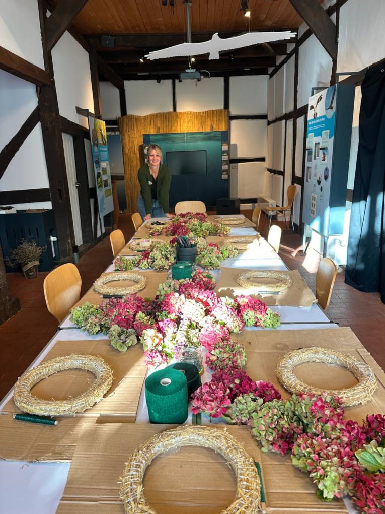 Tisch mit Strohkr&auml;nzen und Bastelmaterial