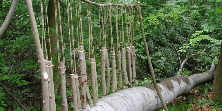 Holzstücke hängen in verschiedenen Längen an einem Ast und bilden so ein Xylophon