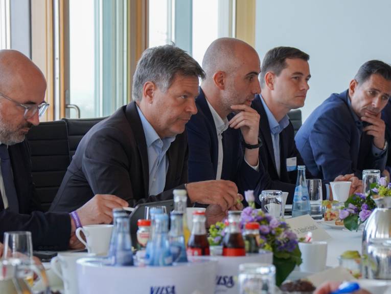 Mehrere Personen an einem Tisch im Gespräch.