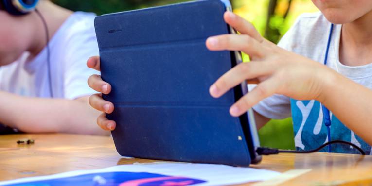 Kinderhände halten einen Tablet-Computer.
