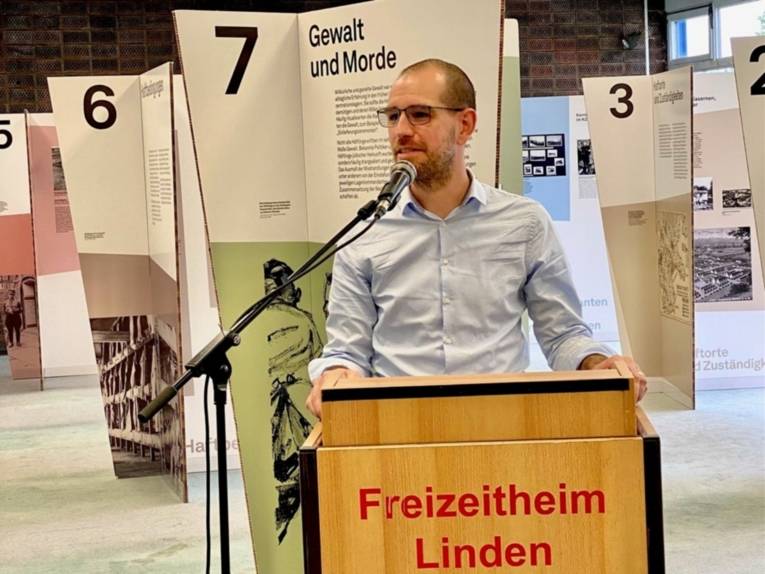 Stefan Wilbricht, Leiter der KZ-Gedenkstätte Moringen, steht am Rednerpult vor der Ausstellung.