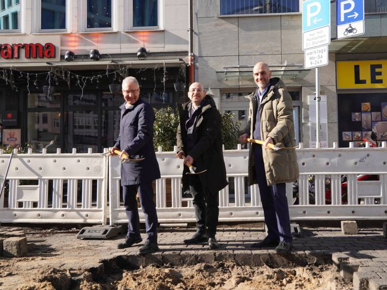 Drei Männer halten Spaten in den Händen.