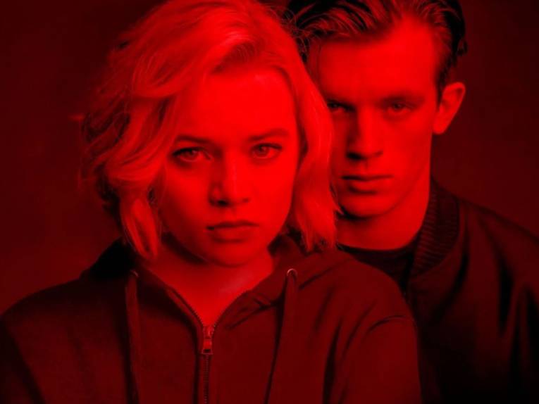 Junge Frau und junger Mann in rotes Licht getaucht.