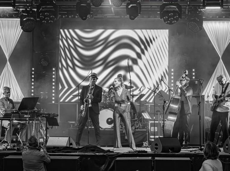 Bühne mit einer Frau am Mikro und vier Männern mit Instrumenten