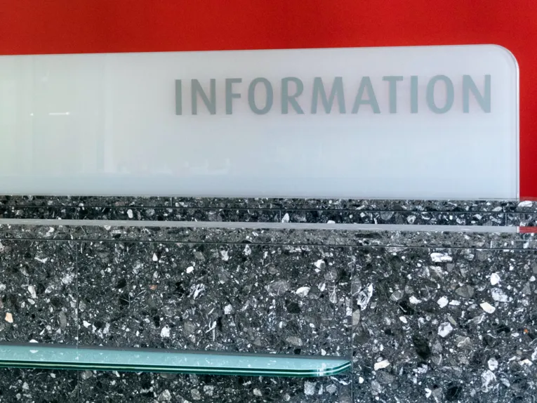 Wort Information vor rotem Hintergrund auf einem steinernen Tresen.