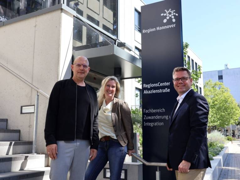Zwei Männer und eine Frau stehen repräsentativ neben einem Schild, auf dem steht: RegionsCenter Akazienstraße