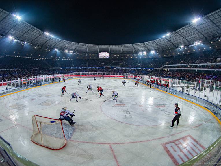 Blick in ein Fußballstadion mit einem Eishockeyfeld, auf dem ein Spiel stattfindet.