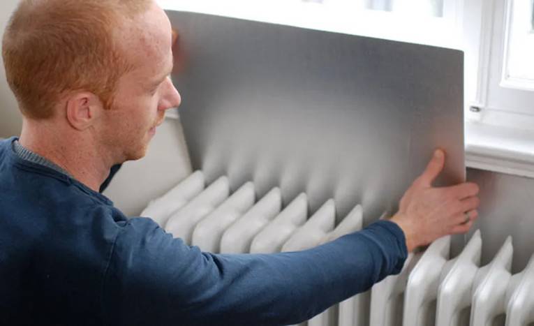 Heizkörper wird an der Wand mit einer Dämmung versehen