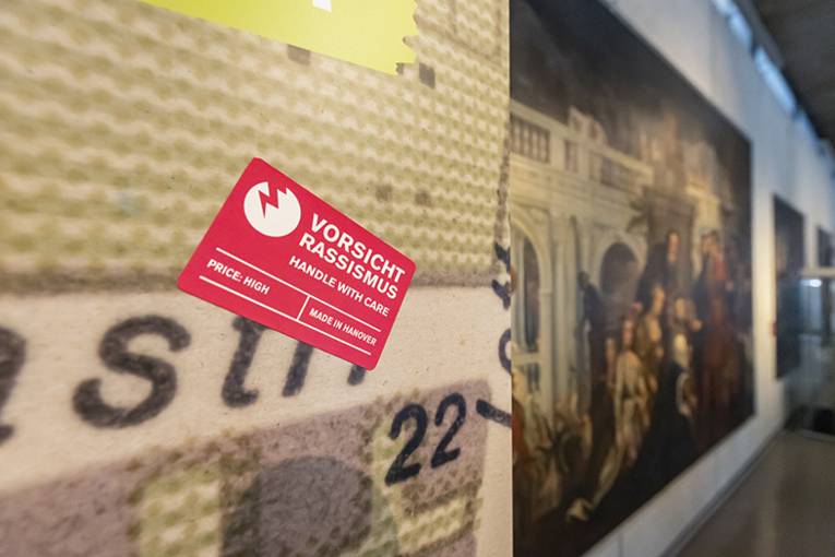 Blick in die Sonderausstellung "Von goldenen Kutschen und kolonialer Vergangenheit: Hannover, England und die Sklaverei", vom 12. Juli bis 13. November 2022 im HMH, hier der rechteckige rote Sticker "Vorsicht Rassismus"
