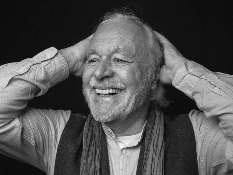 Ein schwarz-weißes Foto von einem Mann, der sich durch die Haare streicht.