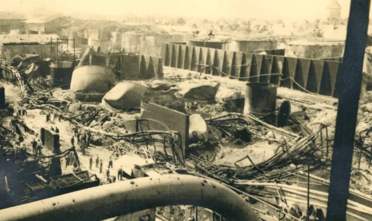 Tr&uuml;mmer einer Tankgruppe nach einem Luftangriff, Sommer 1944. Im Vordergrund Milit&auml;rs und Zivilpersonen, rechts im Hintergrund der Misburger Wasserturm.