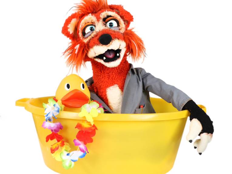 Fuchspuppe mit einem Quietscheentchen in einer Badewanne