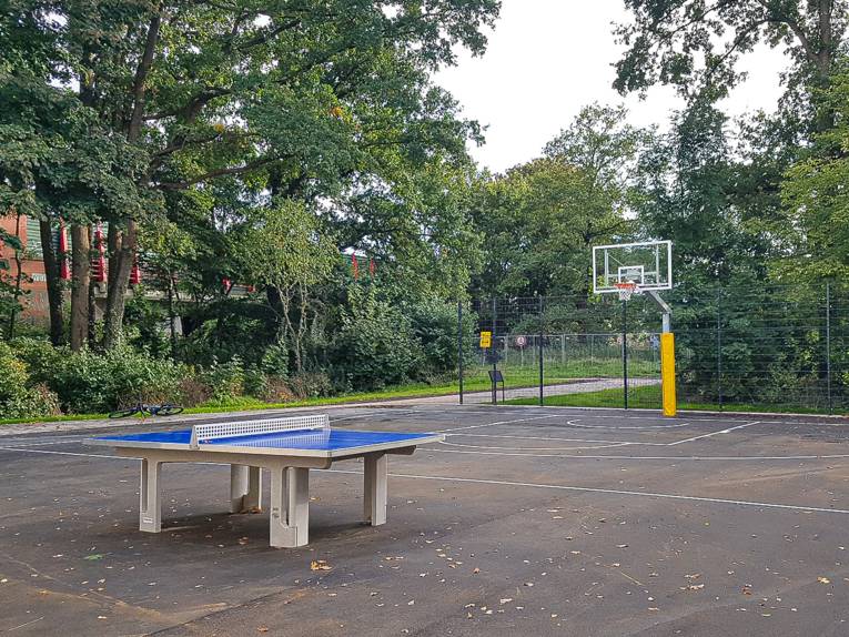 Ein Basketballplatz. Davor eine Tischtennisplatte.