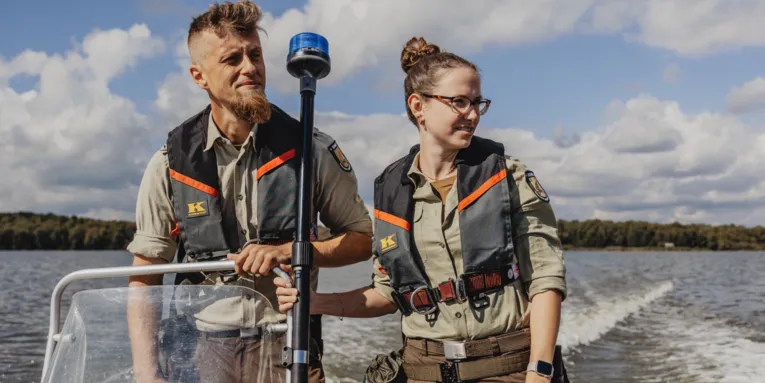 Eine Rangerin und ein Ranger fahren mit einem Boot.