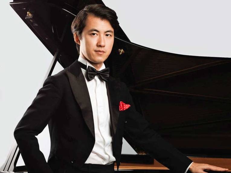 Ein Mann steht an einem Konzertflügel