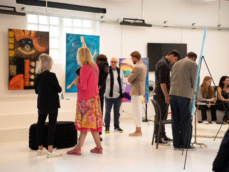 Menschen betrachten in einer Halle Kunstwerke