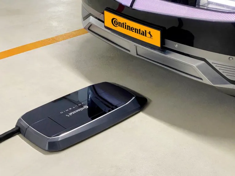 Flache, kastenförmige Lade-Einheit, die vor einem Auto auf dem Boden platziert ist.