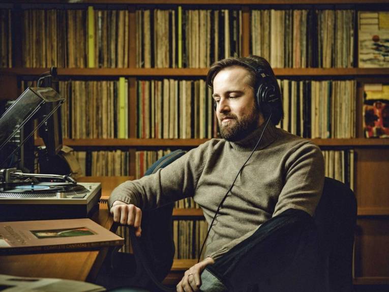 Ein Mann mit Kopfhörern vor einem Plattenspieler