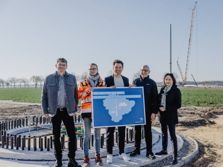 Fünf Personen auf dem Sockel einer Windenergieanlage im Bau