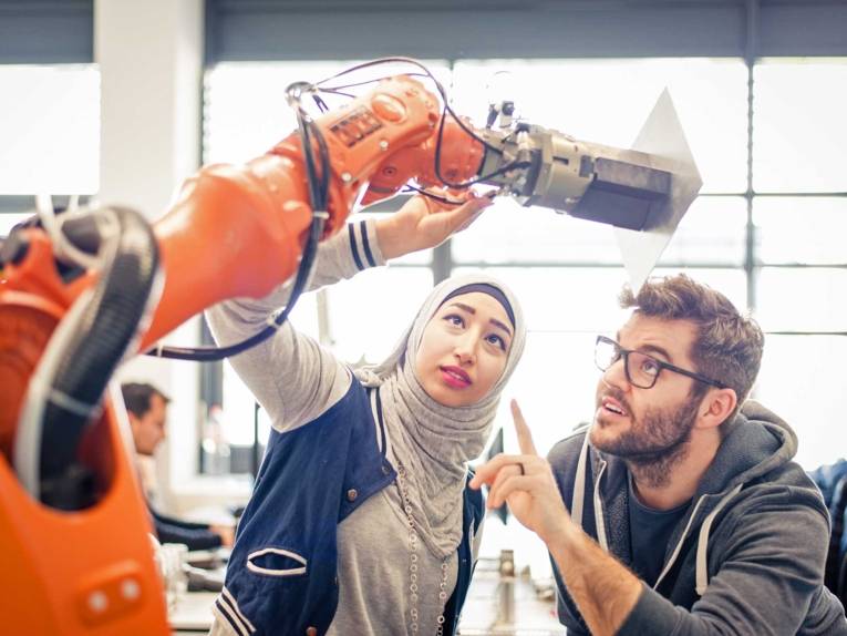 Eine Frau und ein Mann mit einem Industrieroboter.