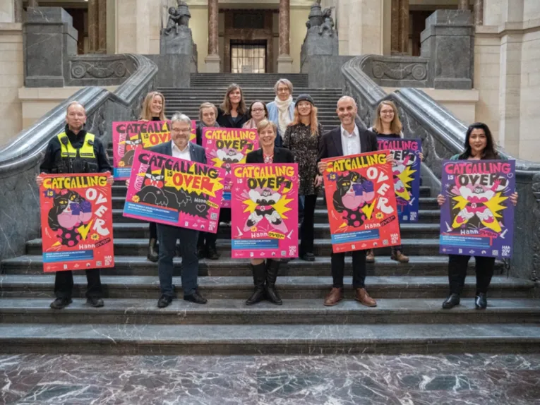 Eine Gruppe von Menschen steht auf einer Treppe, jede Person hält ein Plakat vor sich.