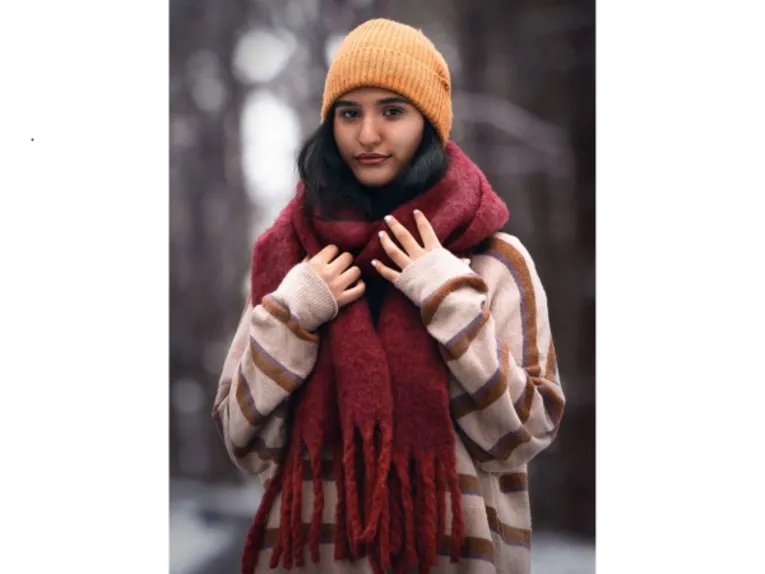 Eine Frau mit Strickpulli, dickem Wollschal und Strickmütze