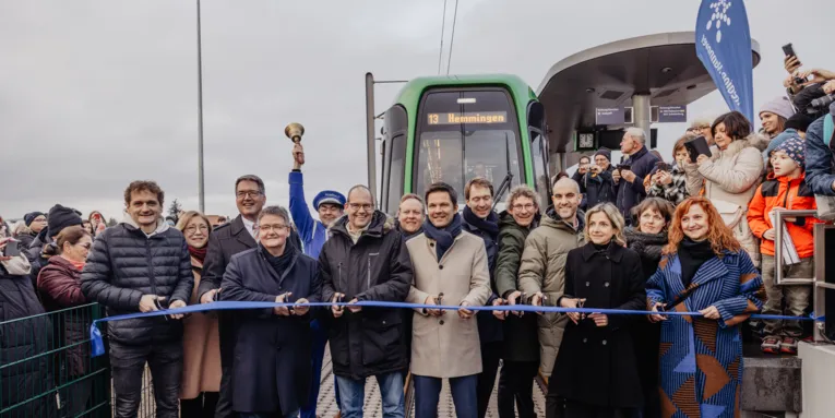 Gruppe von Personen, die ein blaues Band zerschneiden an einer Stadtbahnhaltestelle, vor einer Stadtbahn mit Fahrtzielanzeige Hemmingen