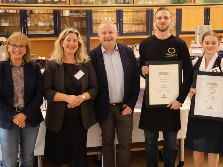 Fünf Personen, zwei davon halten eine Urkunde in der Hand